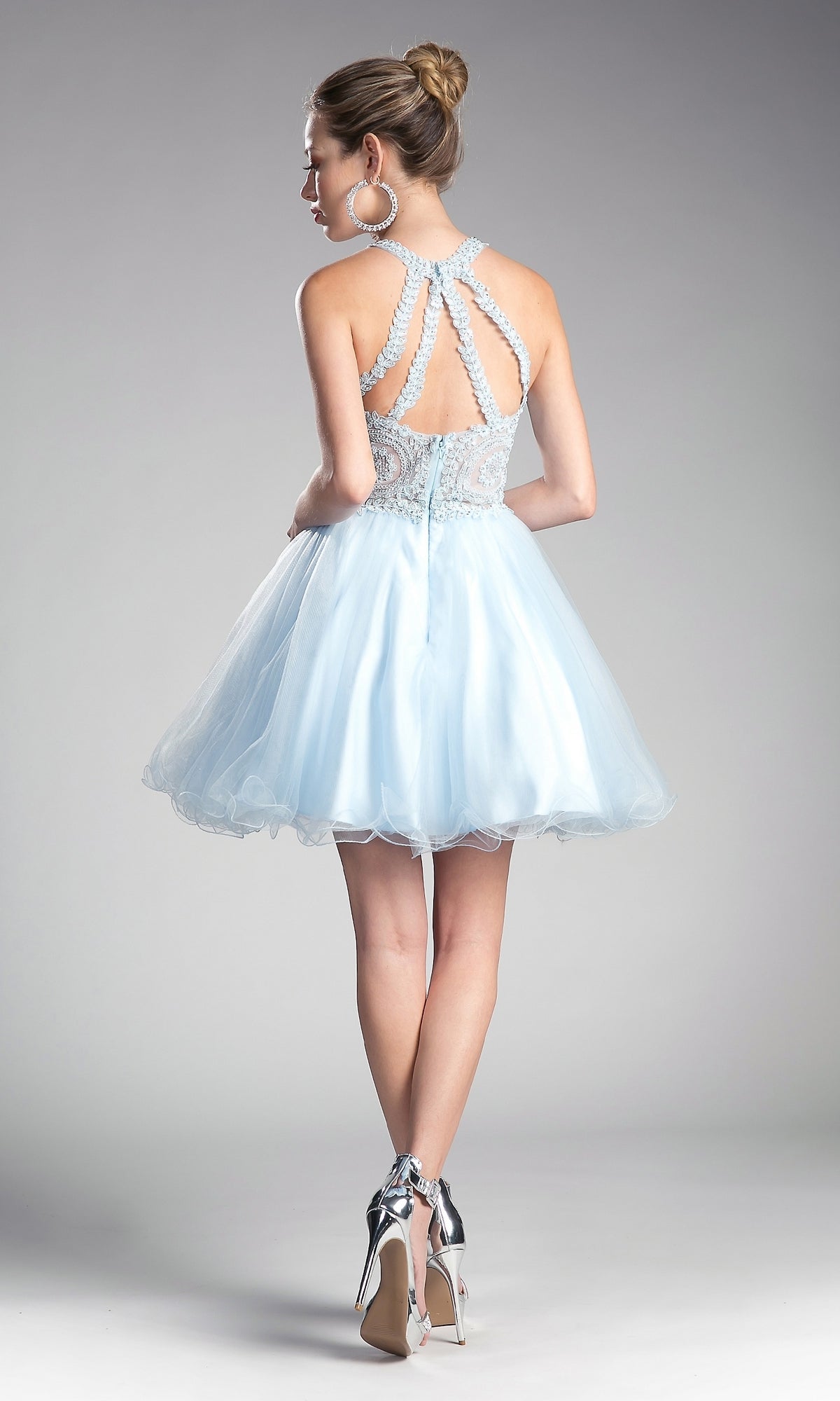 Woman in the High-Neck Short Babydoll Homecoming Dress UJ0119, featuring an embroidered-lace bodice and strappy back, styled with large hoop earrings and silver heels, poses against a plain background.
